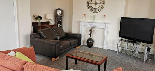a living room with a leather couch and a tv at Westmount 1st North Apt in Scarborough