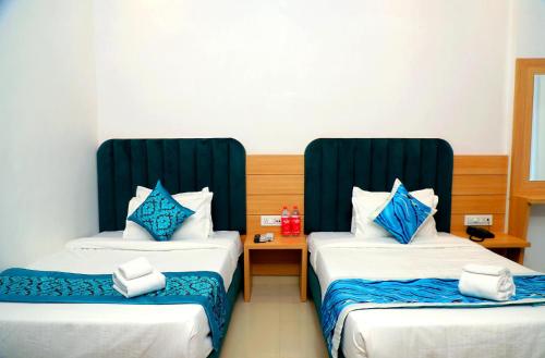 a hotel room with two beds with blue pillows at Hotel Diamond View in Amritsar