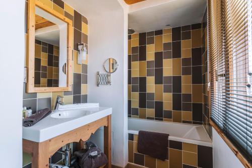 a bathroom with a sink and a tub and a mirror at La Maison Les Peupliers in Courchevel