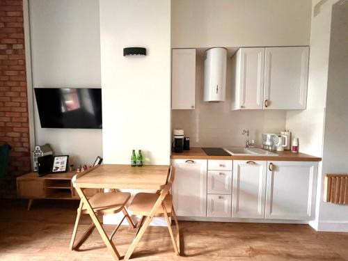 a kitchen with white cabinets and a wooden table at Brick Castle - Apartament Ulrich in Wrocław