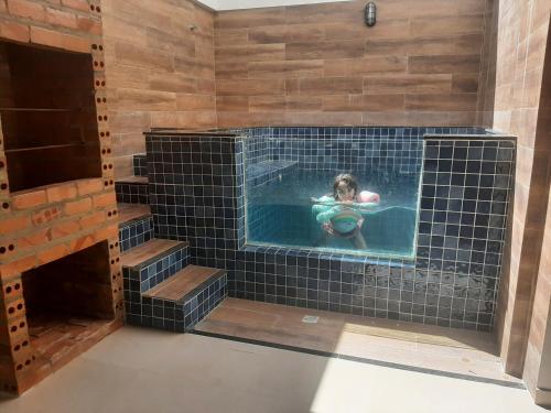a woman in a swimming pool in a black tile tub at Casa com piscina a 500m da praia in Salinópolis