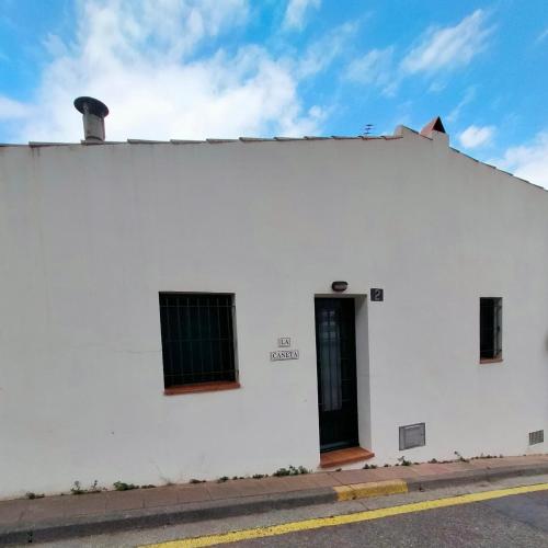 a white building with a black door on a street at La Caseta in Tamariu