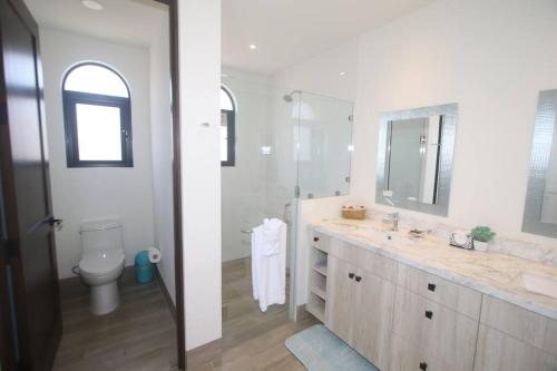 een witte badkamer met een wastafel en een toilet bij Mavila at Quivira Golf & Sea Community plus PB Beach Access on Medano Beach in Cabo San Lucas
