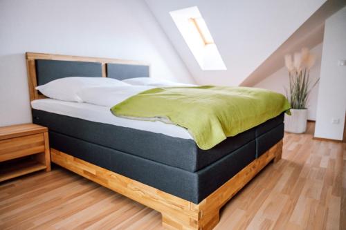 a bedroom with a bed with a green blanket on it at Landhaus dasThomas in Henndorf 