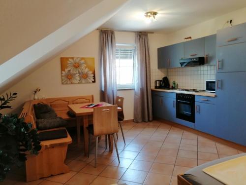 eine Küche und ein Wohnzimmer mit einem Tisch und einem Sofa in der Unterkunft Gästehaus Brunnerhof - Reisen in Eitting