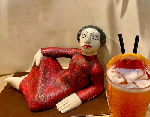 a statue of a woman sitting on a table next to a drink at Locanda degli Artisti Art Hotel in Canazei