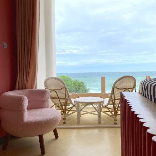 a room with chairs and a table and a view of the ocean at Belika Beach in Hiriketiya
