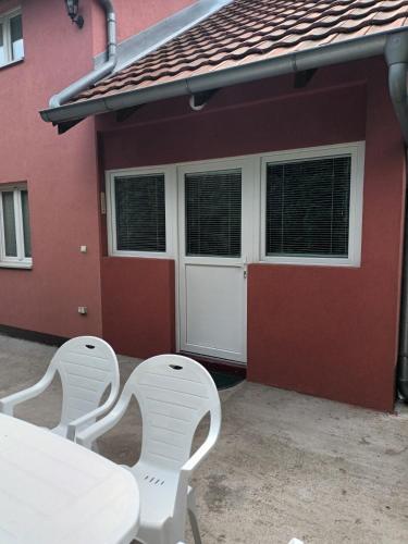 two white chairs and a table in front of a garage at Etno Avlija Srebrno jezero in Zatonje