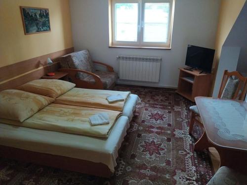 a bedroom with a bed and a living room at Chalupa pod lipami in Terchová
