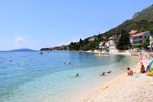 Apartments by the sea Gradac, Makarska - 18877 في غراداك: مجموعة من الناس في المياه على الشاطئ