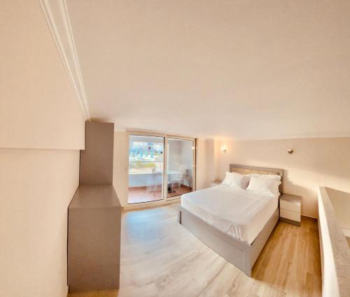 - une chambre avec un lit blanc et une grande fenêtre dans l'établissement Flors Apartments, à Durrës