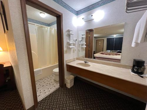 La salle de bains est pourvue d'un lavabo, de toilettes et d'un miroir. dans l'établissement Americas Inn Bardstown, à Bardstown