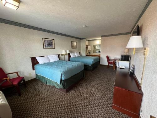 um quarto de hotel com duas camas e uma mesa e cadeiras em Americas Inn Bardstown em Bardstown