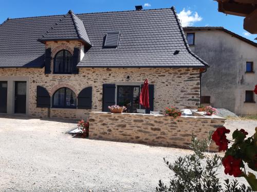 a stone house with a stone retaining wall in front of it at gite de La Carrière in Saint-Julien-de-Piganiol