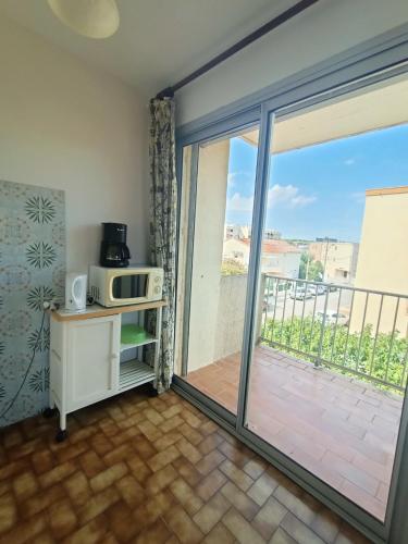 Cette chambre dispose d'une porte s'ouvrant sur un balcon avec un four micro-ondes. dans l'établissement Appartement pour 4 personnes à 50m de la plage Narbonne Plage 4LP2A8, à Narbonne-Plage