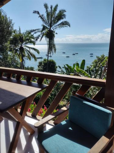 a chair on a balcony with a view of the ocean at Pousada Residence Vila das Flores in Morro de São Paulo