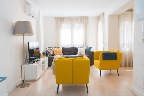 ein Wohnzimmer mit einem Sofa und zwei gelben Stühlen in der Unterkunft Precioso Apartamento 2 hab. en Malaga Centro in Málaga