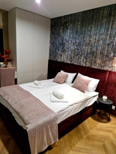 a bedroom with a large bed with white sheets and pink pillows at Apartament Zamojski Rynek 21 in Zamość
