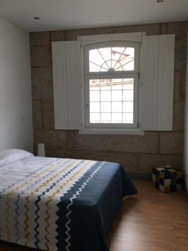 1 dormitorio con cama y ventana en Apartamento, Praça Dom Duarte 8, Viseu, Portugal, en Viseu