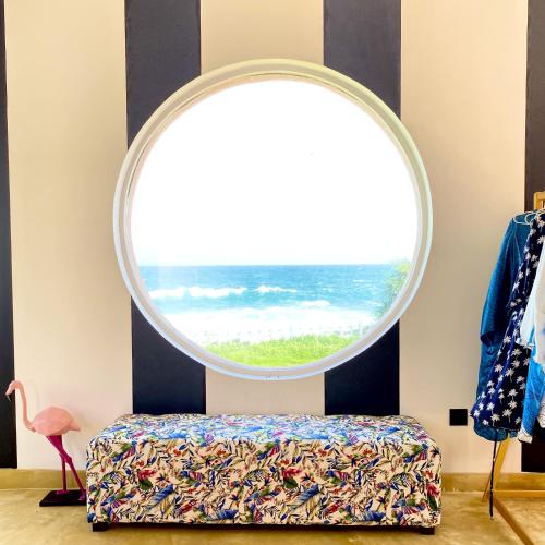an oval window in a room with a bed and a round mirror at Belika Beach in Hiriketiya