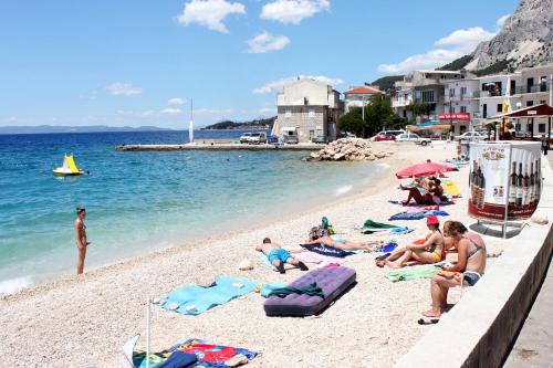 eine Gruppe von Menschen, die am Strand sitzen in der Unterkunft Seaside holiday house Drasnice, Makarska - 10359 in Drašnice