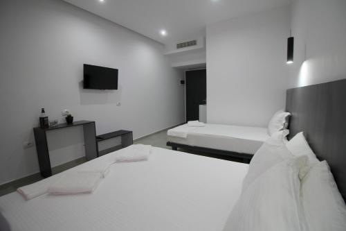 een witte kamer met 2 bedden en een televisie bij Art De Jon Rooms in Sarandë