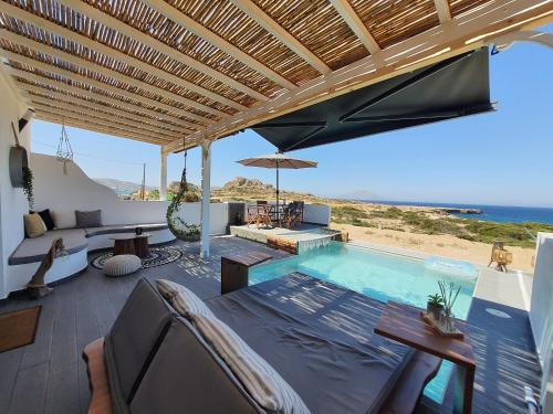 an outdoor patio with a pool and an umbrella at Tramonto Luxury Villa No2 - Breathtaking sunset view in Karpathos