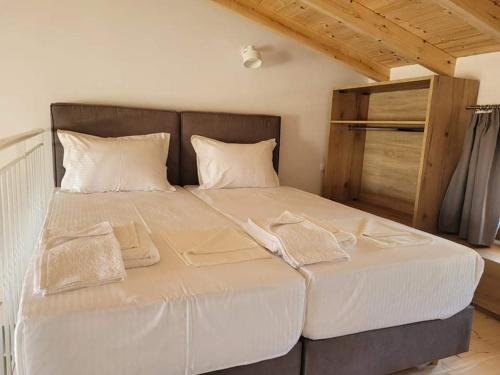 a large bed with white sheets and pillows on it at Petrina Bolosis in Palaiókastron