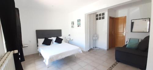 - une chambre avec un lit blanc et un canapé noir dans l'établissement LA-CIGALE-ARGELES studio La Massane, à Plage dʼArgelès