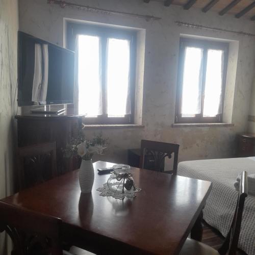 a dining room table with a vase of flowers on it at Casale della rosa in Loreto