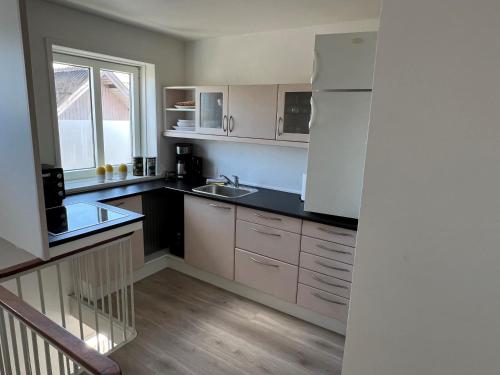 a kitchen with white cabinets and a sink and a window at Hyggelig lejlighed in Bindslev