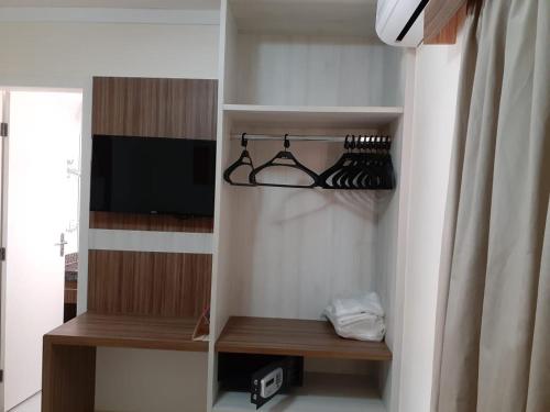 a room with a closet with shelves and a tv at Caldas Novas Lacqua Di Roma IV - 2 banheiros e cozinha, piscina 24 horas in Caldas Novas