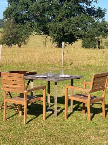 a wooden table with two chairs and a table with glasses at Le Maissin 1876 in Paliseul