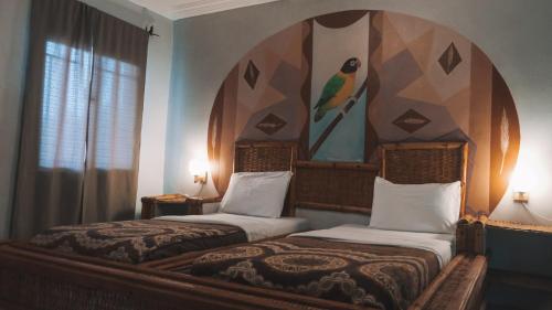 2 camas en un dormitorio con una pintura en la pared en Bamboo Garden Hotel, en Serekunda
