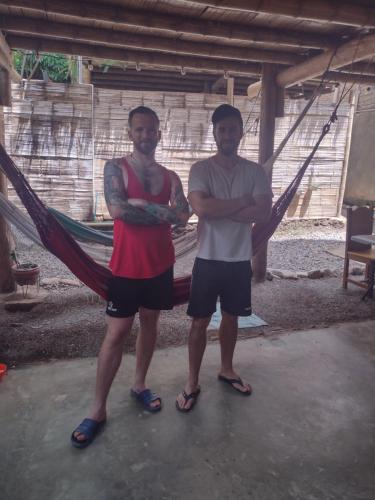 two men standing next to each other in a hammock at Cabaña Buenos Aires in Palomino