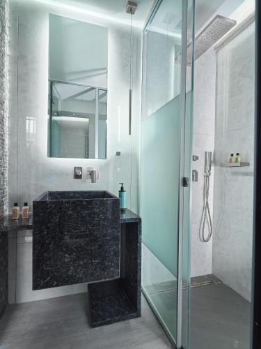a bathroom with a glass shower and a sink at Nautilux Rethymno by Mage Hotels in Rethymno Town