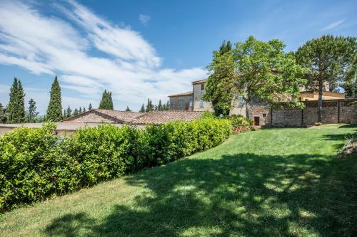 a yard with grass and bushes and a house at Castel Pietraio in Monteriggioni