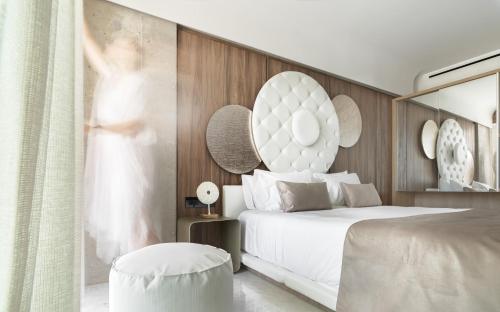 a hotel room with a bed and a woman looking out the window at Nautilux Rethymno by Mage Hotels in Rethymno Town