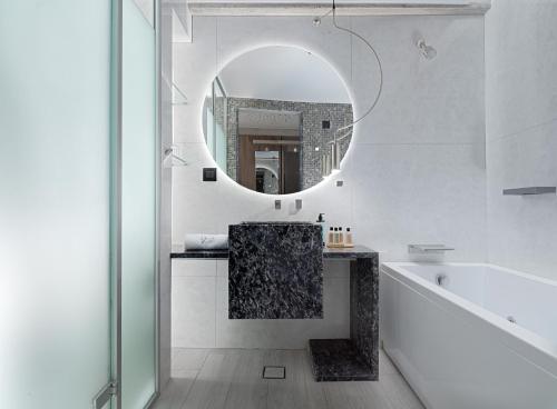 a bathroom with a mirror and a tub and a sink at Nautilux Rethymno by Mage Hotels in Rethymno Town