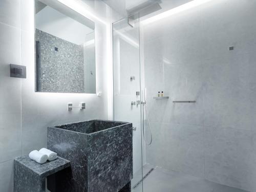 a bathroom with a shower and a black marble tub at Nautilux Rethymno by Mage Hotels in Rethymno Town