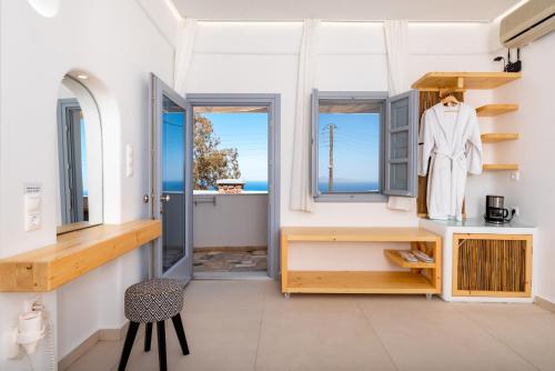 a room with a white coat on a rack and windows at Hotel Thira in Fira