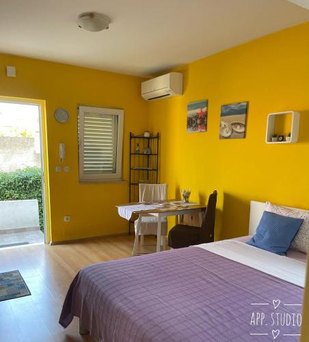 a bedroom with a bed and a table and yellow walls at Apartments Mery in Rovinj