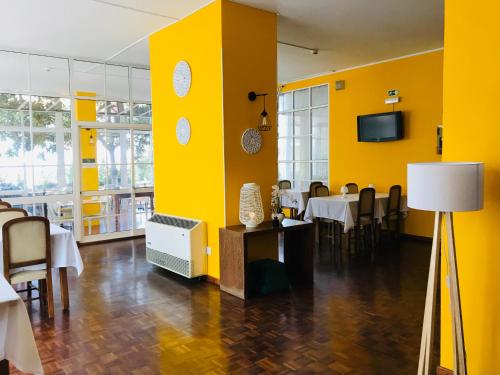 uma sala de jantar com paredes amarelas, mesas e cadeiras em Monte Verde no Funchal