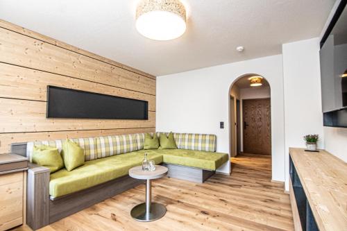 a living room with a green couch and a flat screen tv at Der Postwirt in Söll