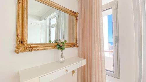 a mirror and a vase with flowers on a dresser at Magnífico apartamento a 35m da praia - Apart. Isa in Albufeira