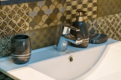 a sink with a faucet and a cup on it at Main square 5 star luxury apartment with view in Cluj-Napoca