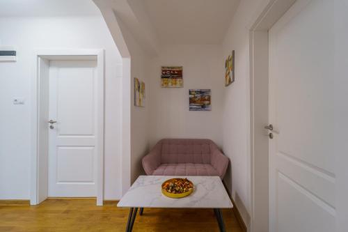 a room with a pink couch and a table with a pizza on it at Main square 5 star luxury apartment with view in Cluj-Napoca