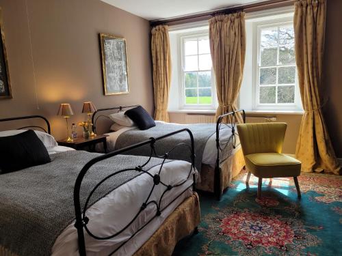 a bedroom with two beds and a chair and a window at The Old Vicarage in Kington