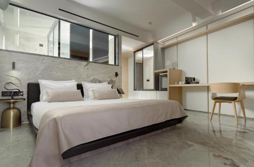 a bedroom with a large white bed and a chair at Nautilux Rethymno by Mage Hotels in Rethymno Town