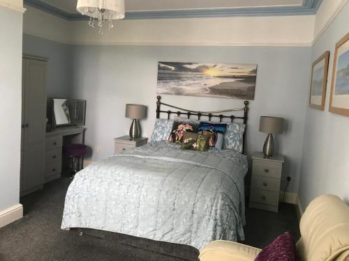 een slaapkamer met een bed en 2 lampen en een bank bij Craig-y-Mor in Criccieth